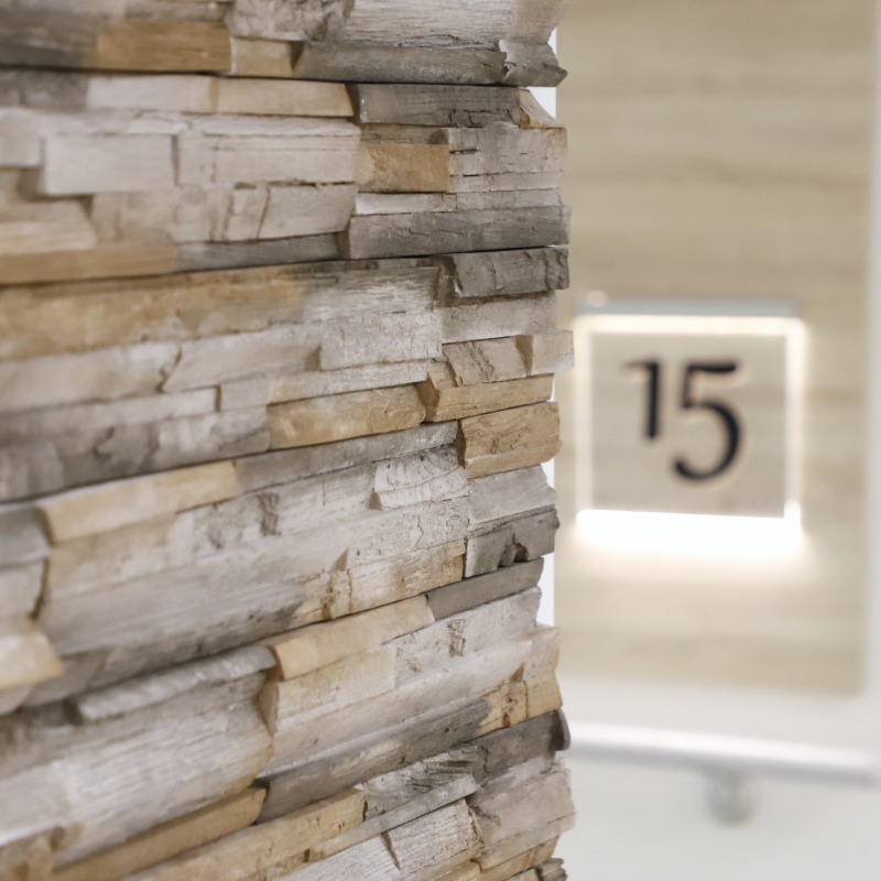 Eine Wand aus Holzplanken im Vordergrund, im Hintergrund eine leuchtende Tafel mit der Nummer 15.