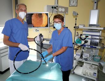 Ärzte in OP-Kleidung mit Endoskopiegerät in einem Labor oder Behandlungsraum.