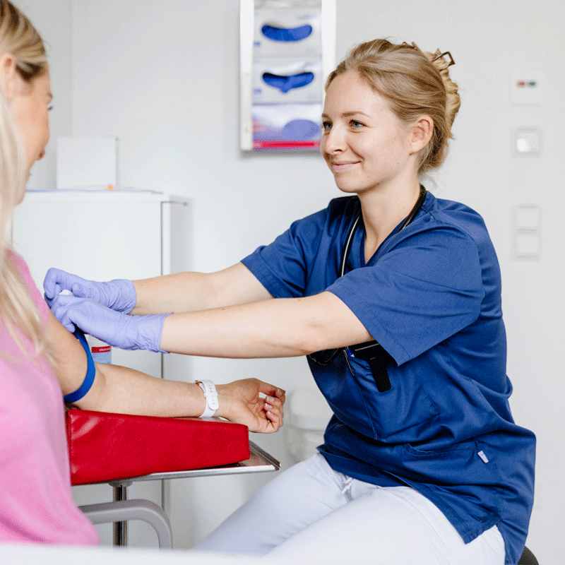 Medizinisches Personal legt Patientin eine Blutdruckmanschette an.