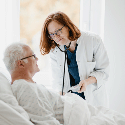 Eine Ärztin untersucht einen älteren Mann im Krankenhaus.