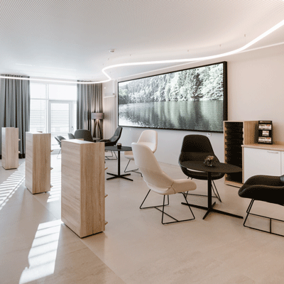 Moderne Lounge mit Sitzgelegenheiten, großen Bild an der Wand, hellem Boden und viel natürlichem Licht.