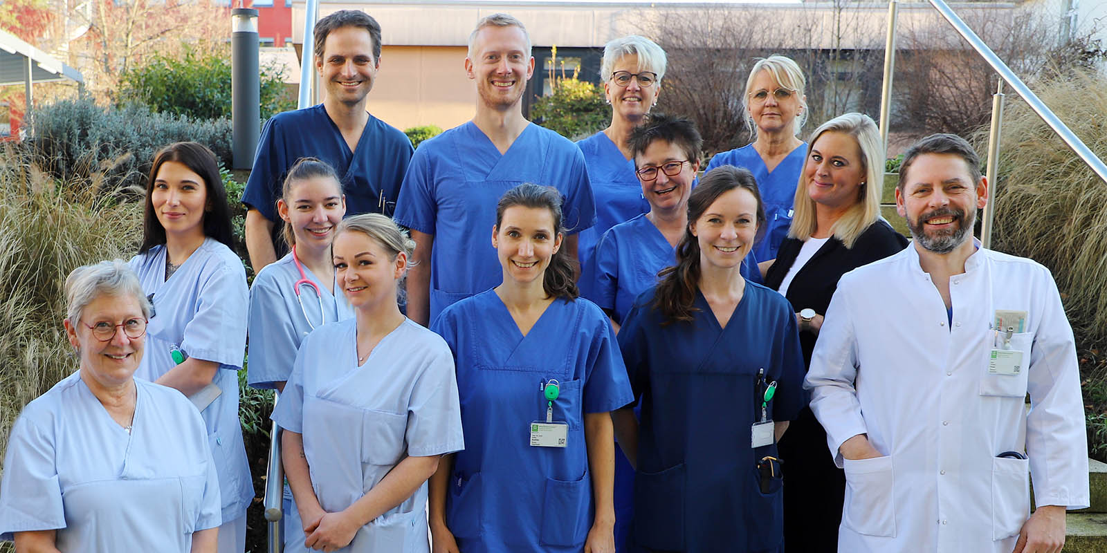 Eine Gruppe von medizinischem Personal in blauer und weißer Berufskleidung steht draußen zusammen.