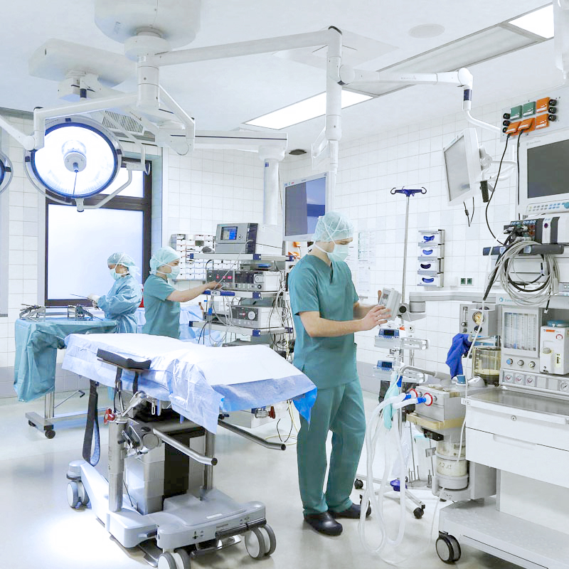 Ein Operationssaal mit medizinischem Personal in OP-Kleidung, umgeben von moderner Ausrüstung und Monitoren.