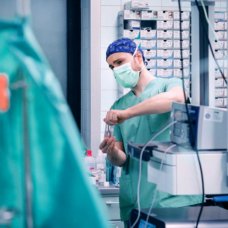 Ein Chirurg in OP-Kleidung arbeitet im Operationssaal mit medizinischer Ausrüstung.