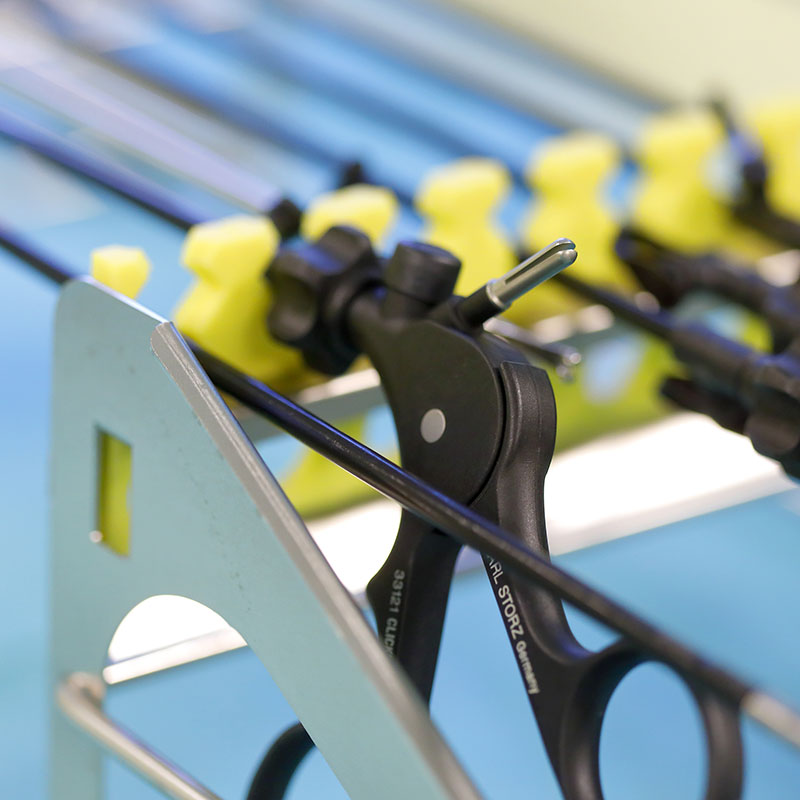 Chirurgische Instrumente mit gelben Halterungen auf einem Metallgestell.