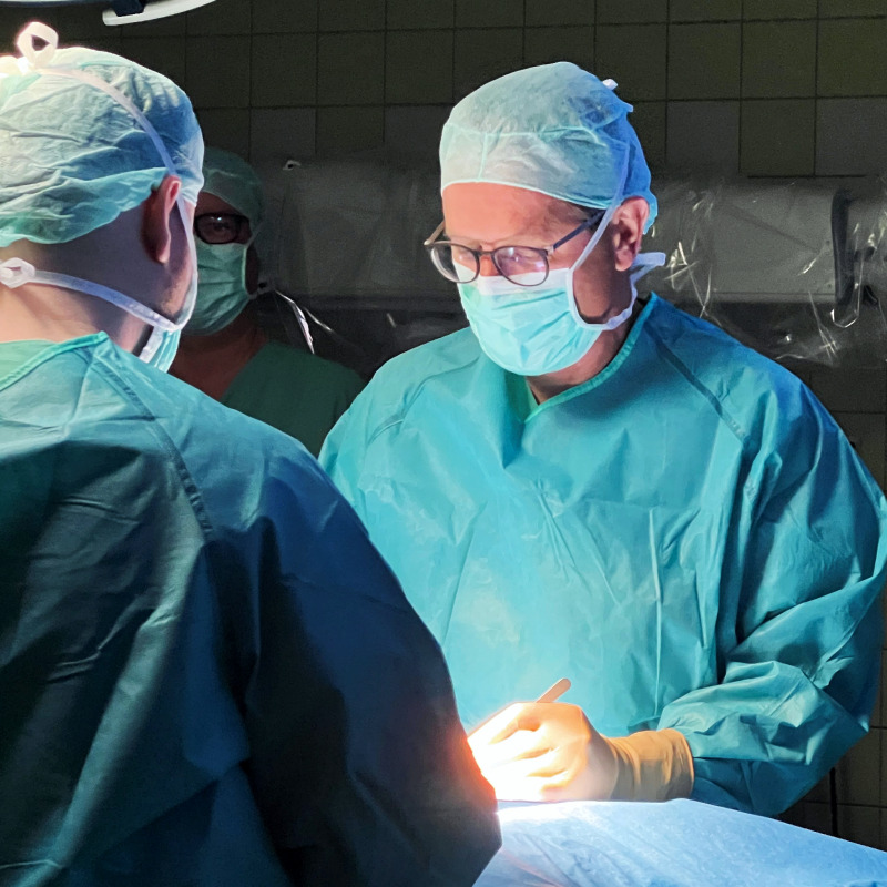 Ärzte in OP-Kleidung führen eine Operation durch, konzentrieren sich auf den Eingriff.