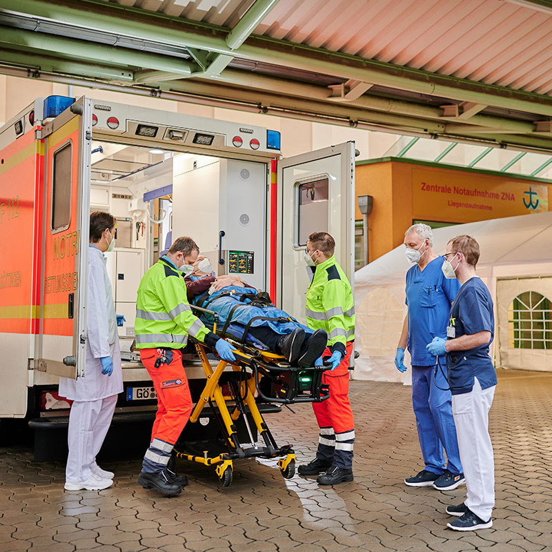 Sanitäter laden einen Patienten in einen Krankenwagen vor der Notaufnahme.