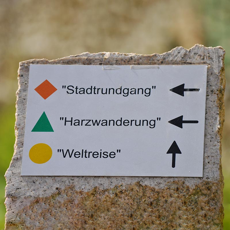 Schild mit Pfeilen: "Stadtrundgang", "Harzwanderung", "Weltreise".