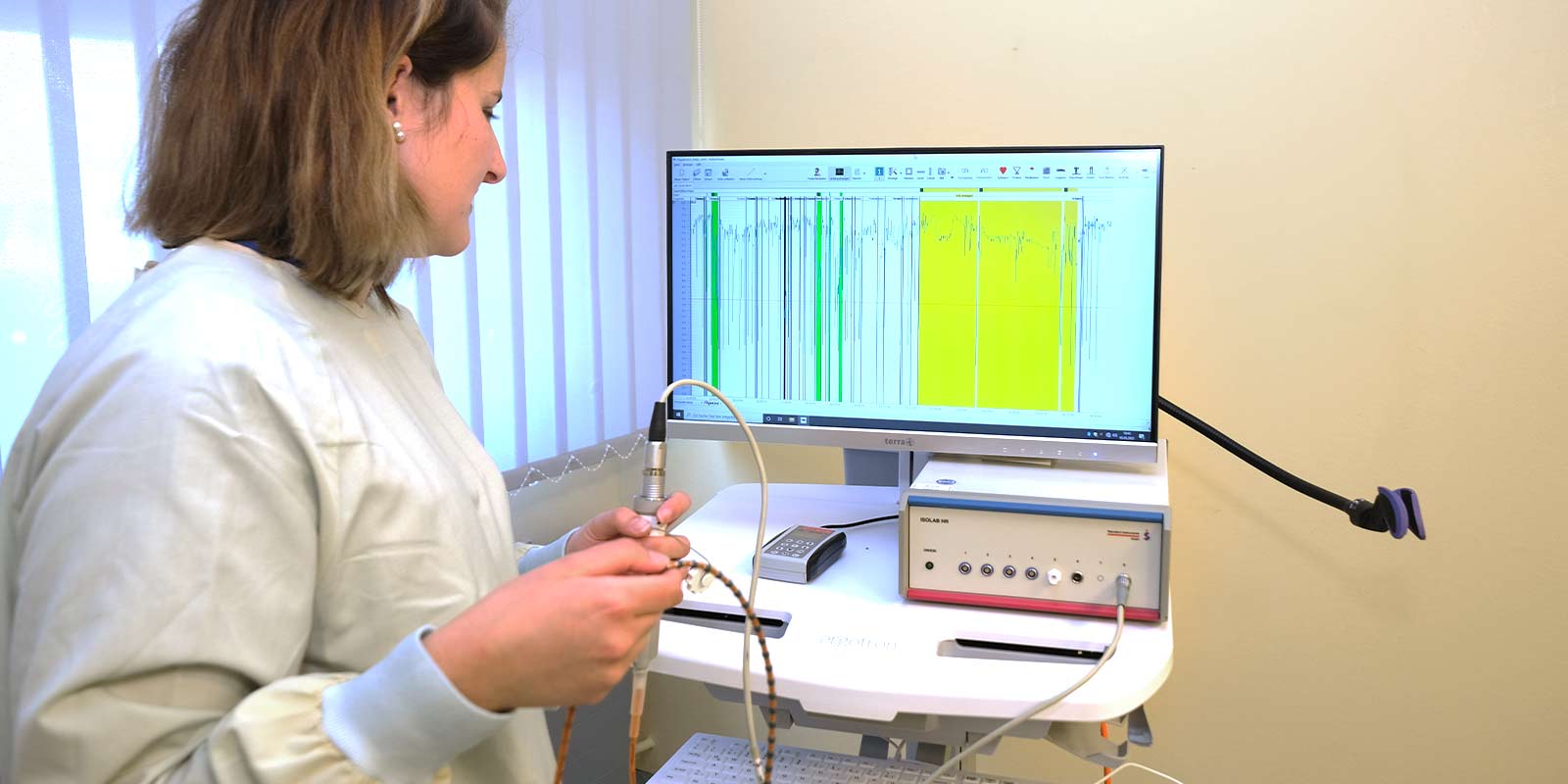 Eine Person bedient ein medizinisches Gerät mit einem Bildschirm, der grafische Daten anzeigt.