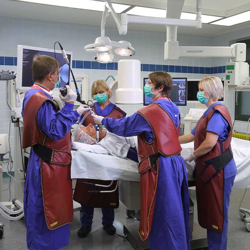 Ärzte in Kitteln und Schürzen führen in einem Krankenhaus eine medizinische Untersuchung an einem Patienten durch.