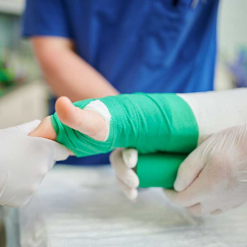 Eine Person legt jemandem einen grünen Gipsverband an einem Arm an.