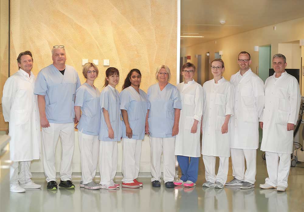 Eine Gruppe von medizinischem Personal in weißen Kitteln steht in einem Flur.