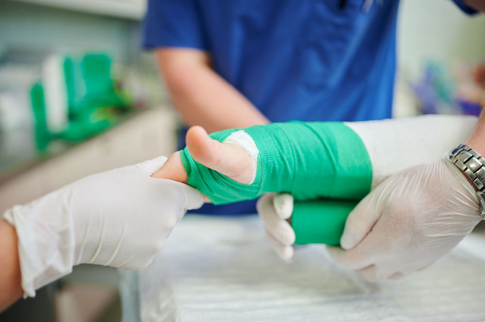 Ein Gipsverband wird auf einen Arm angelegt, während medizinische Fachkräfte Handschuhe tragen.