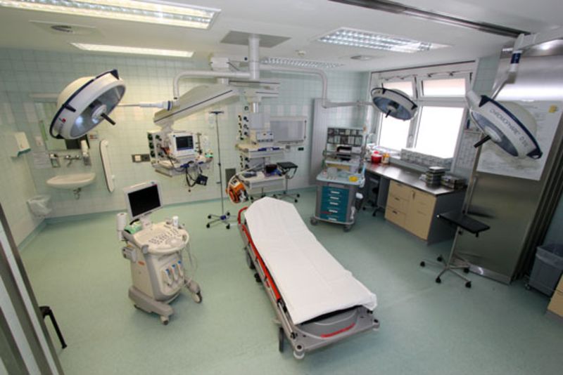 Ein moderner Operationssaal mit medizinischer Ausrüstung, OP-Tisch, Monitoren und OP-Lampen.