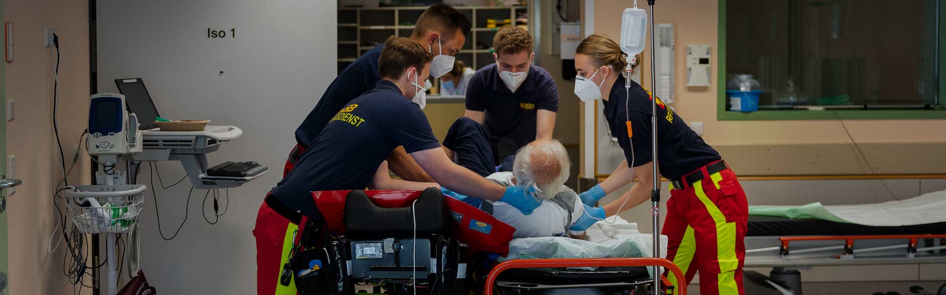 Sanitäter betreuen einen älteren Mann auf einer Trage im Krankenhaus.