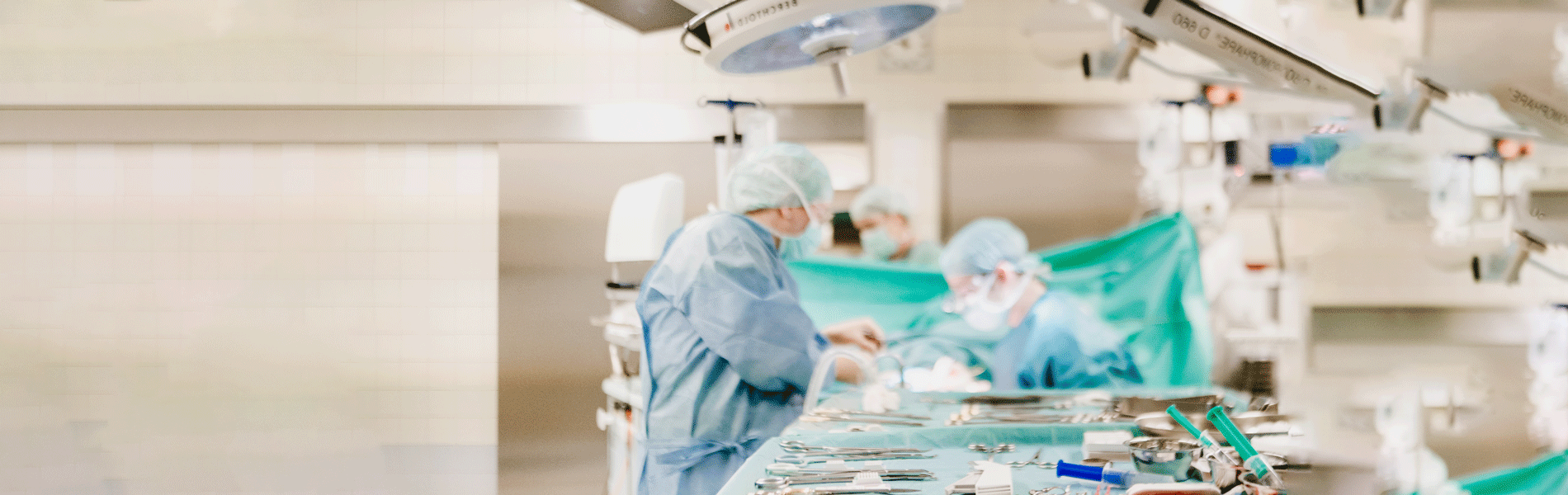 Chirurgen in einem OP-Saal bei der Arbeit, umgeben von medizinischen Instrumenten und sterilen Tüchern.