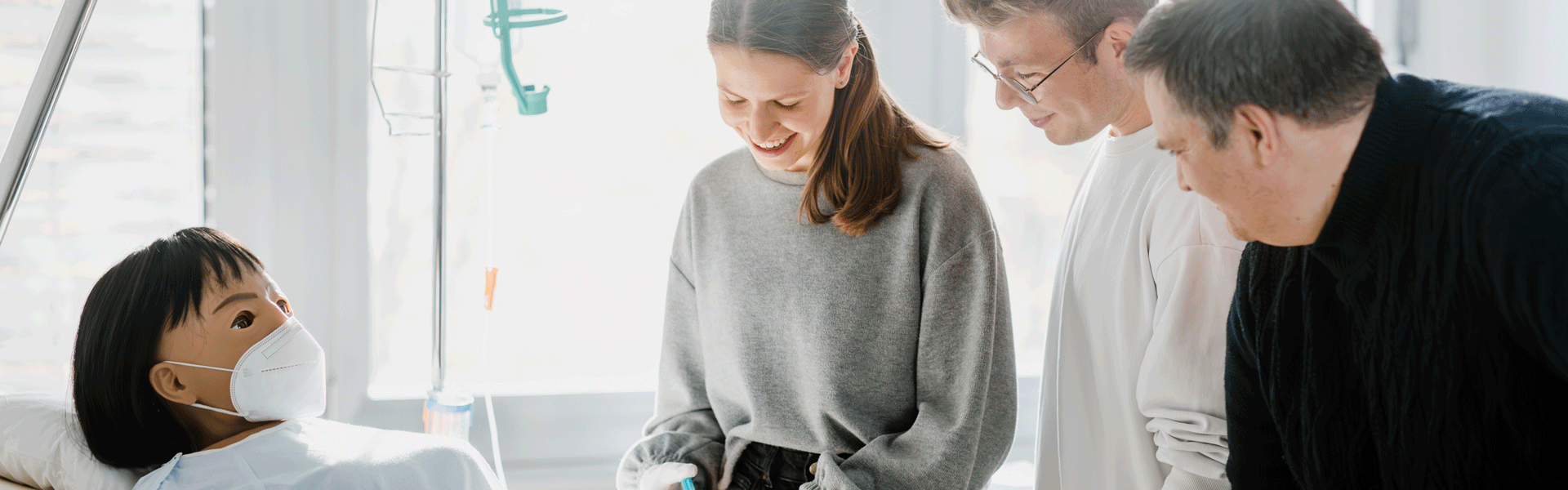 Medizinstudenten üben an einem Krankenpflegemodell mit Maske, während sie von Lehrern betreut werden.