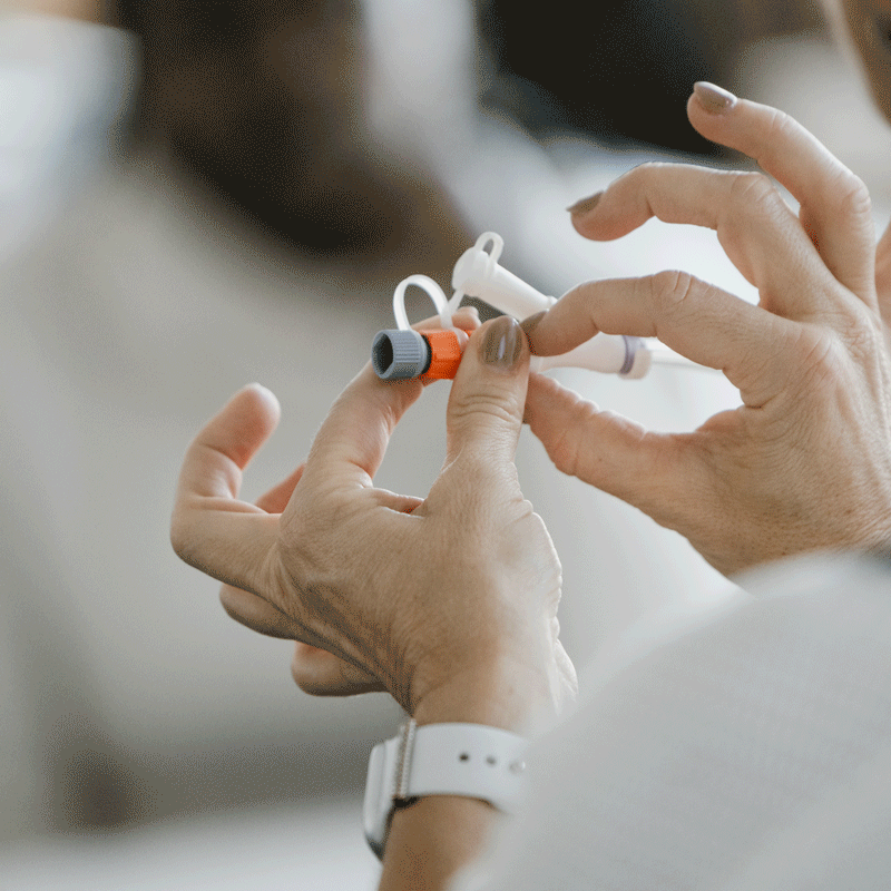 Hände halten medizinische Röhrchen und Geräte.