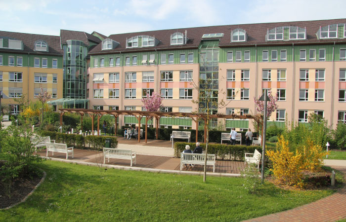 Ein modernes Gebäude mit Sitzbänken und einem Garten im Vordergrund.