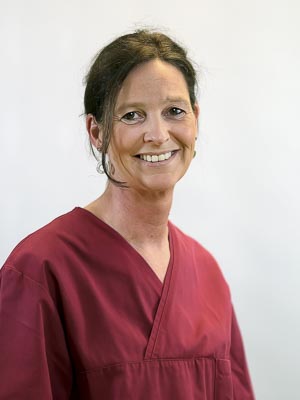 Es ist eine Person in roter Arbeitskleidung, die lächelt.