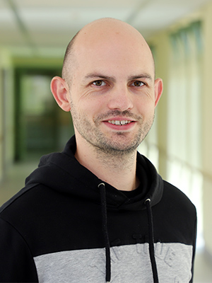 Ein Mann in einem Korridor trägt einen schwarzen Hoodie.